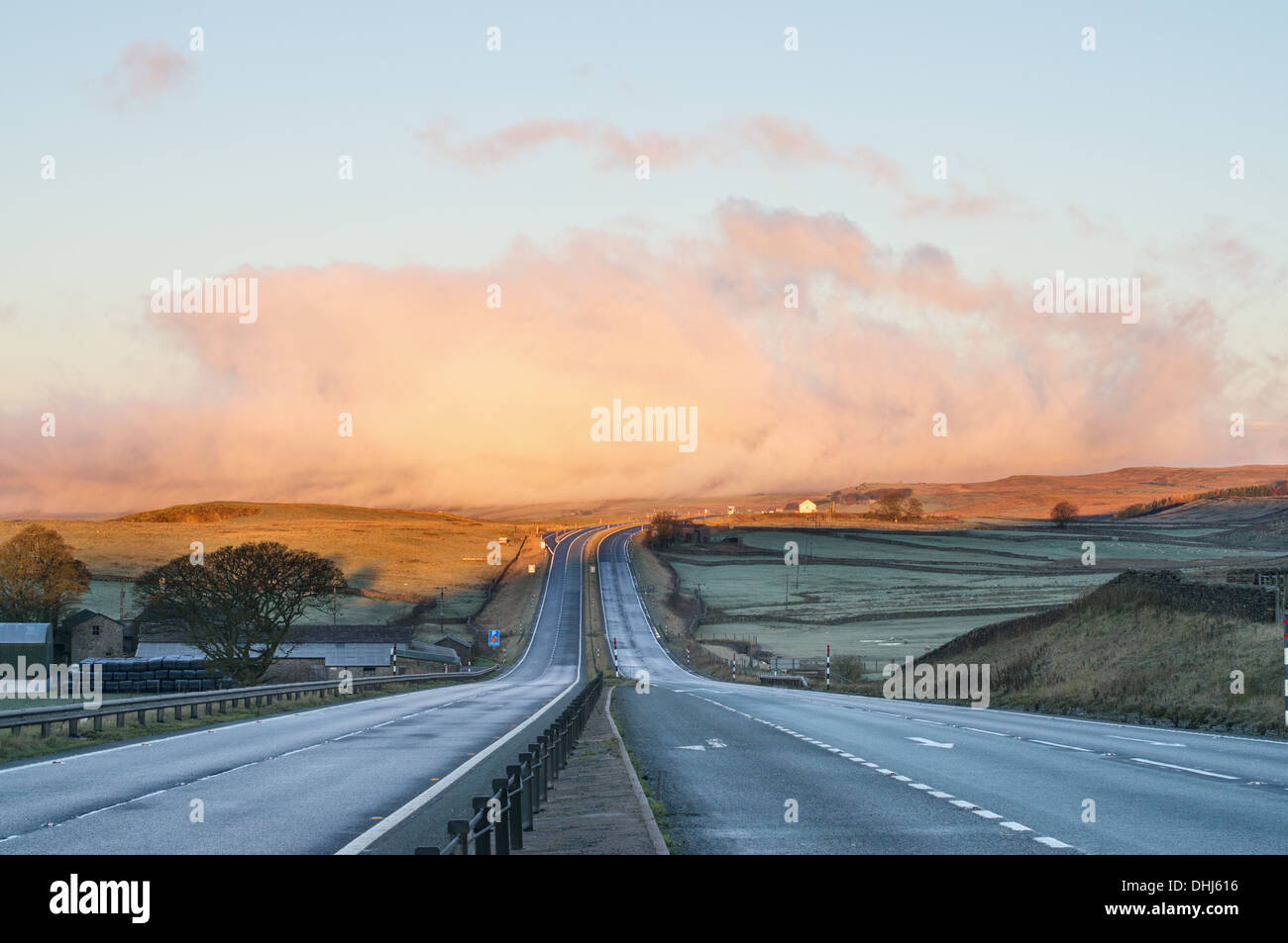 La mattina presto vista lungo un vuoto A66 stradale attraverso Bowes Moor con nuvole all'orizzonte, nell'Inghilterra del Nord, Regno Unito Foto Stock