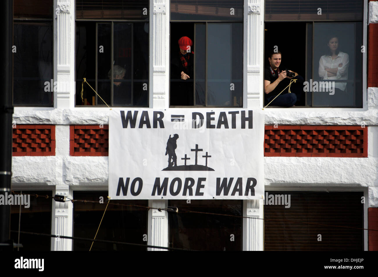 Un banner antiwar pende da un edificio durante il Giorno del Ricordo cerimonie in Piazza della Vittoria nel centro cittadino di Vancouver, British Columbia, Canada Foto Stock