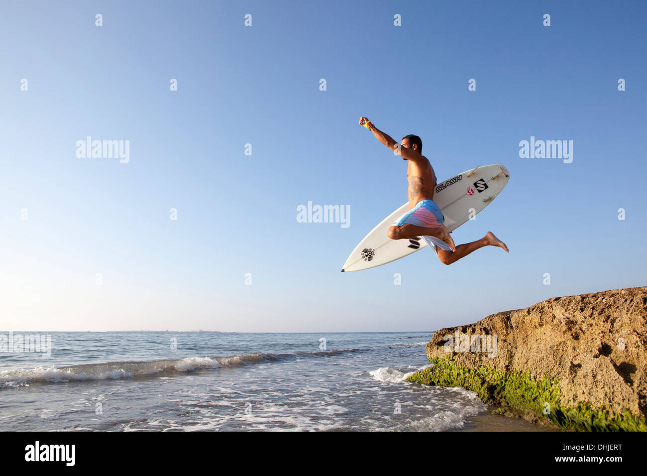 L'uomo saltare in acqua con la sua tavola da surf Foto Stock