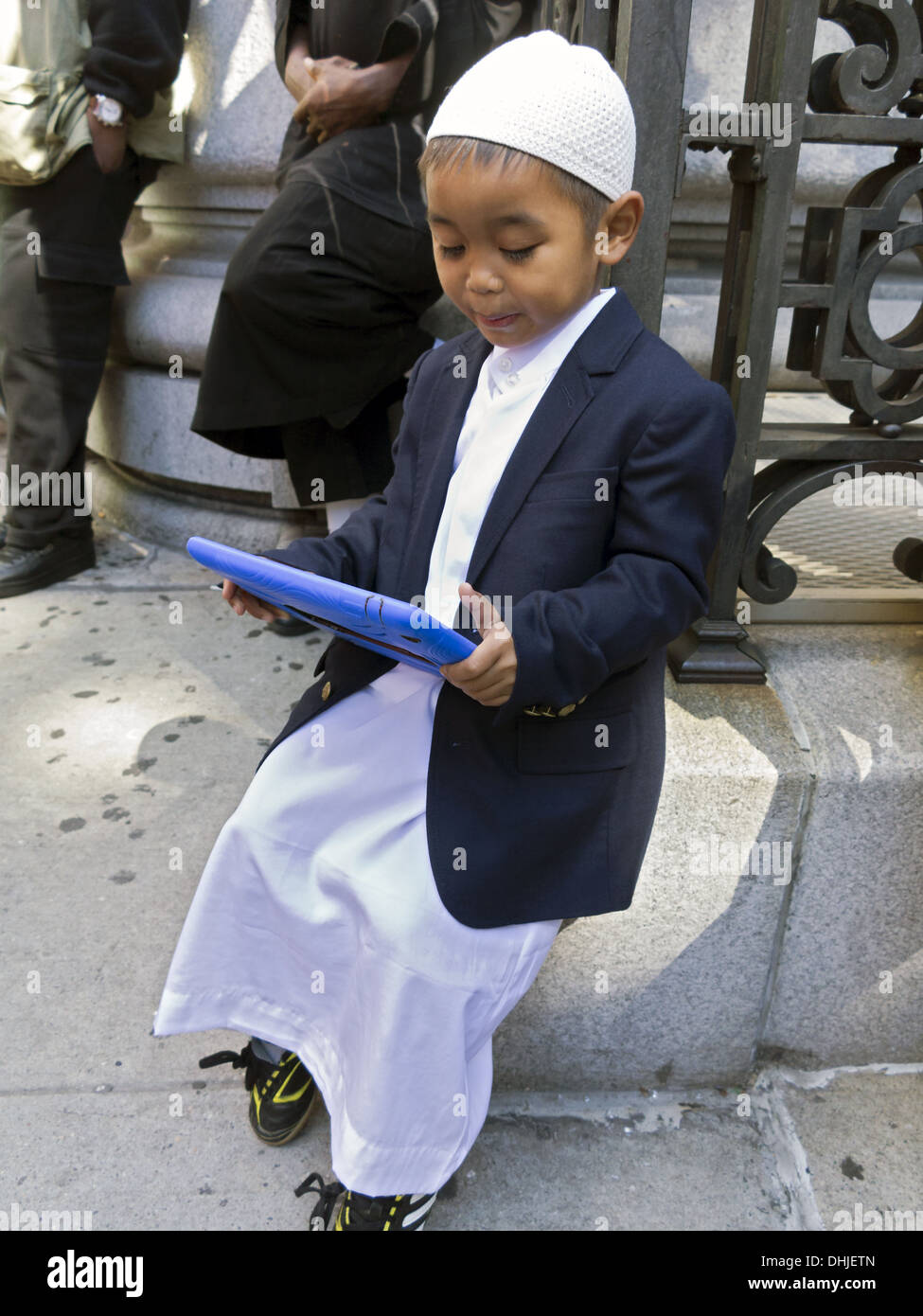 Ragazzo indonesiano nella preghiera i vestiti la riproduzione di gioco prima che il musulmano giorno Parade, New York City, 2013. Foto Stock