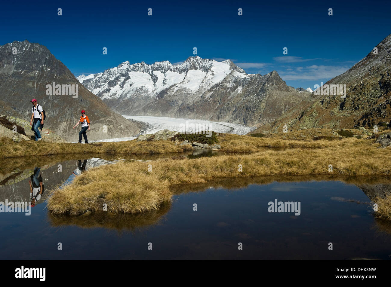 Escursionismo coppia al lago Bettmersee, Bettmeralp, in background Oberland Bernese, Canton Vallese, Svizzera, Europa Foto Stock