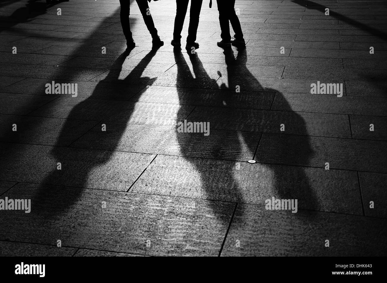 Le gambe e le ombre di tre persone in piedi insieme Foto Stock