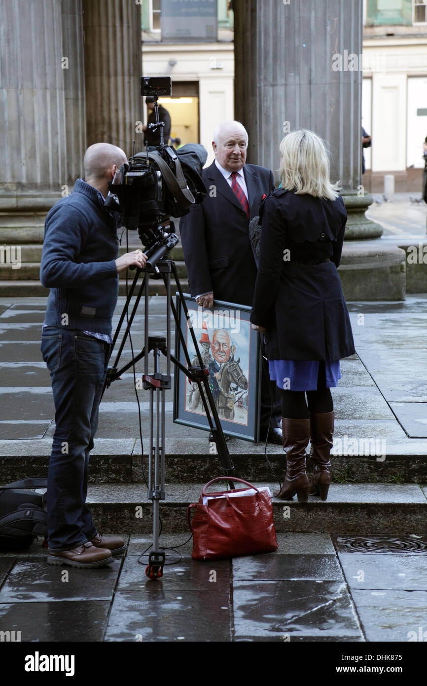 Royal Exchange Square / Queen Street, Glasgow, Scozia, Regno Unito, martedì, 12 novembre, 2013. Glasgow District Council ha invertito la decisione di sollevare la base recante la statua del duca di Wellington per cercare di impedire a chiunque di collocare un cono di traffico sulla sua testa. Alex Mosson, centro, ex Lord Provost di Glasgow, intervistato da Catriona Renton per BBC Scotland, destra Foto Stock
