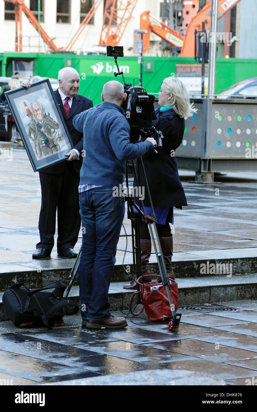 Royal Exchange Square / Queen Street, Glasgow, Scozia, Regno Unito, martedì, 12 novembre, 2013. Glasgow District Council ha invertito la decisione di sollevare la base recante la statua del duca di Wellington per cercare di impedire a chiunque di collocare un cono di traffico sulla sua testa. Alex Mosson, a sinistra, un ex Lord Provost di Glasgow, intervistato da Catriona Renton per BBC Scotland, a destra. Foto Stock