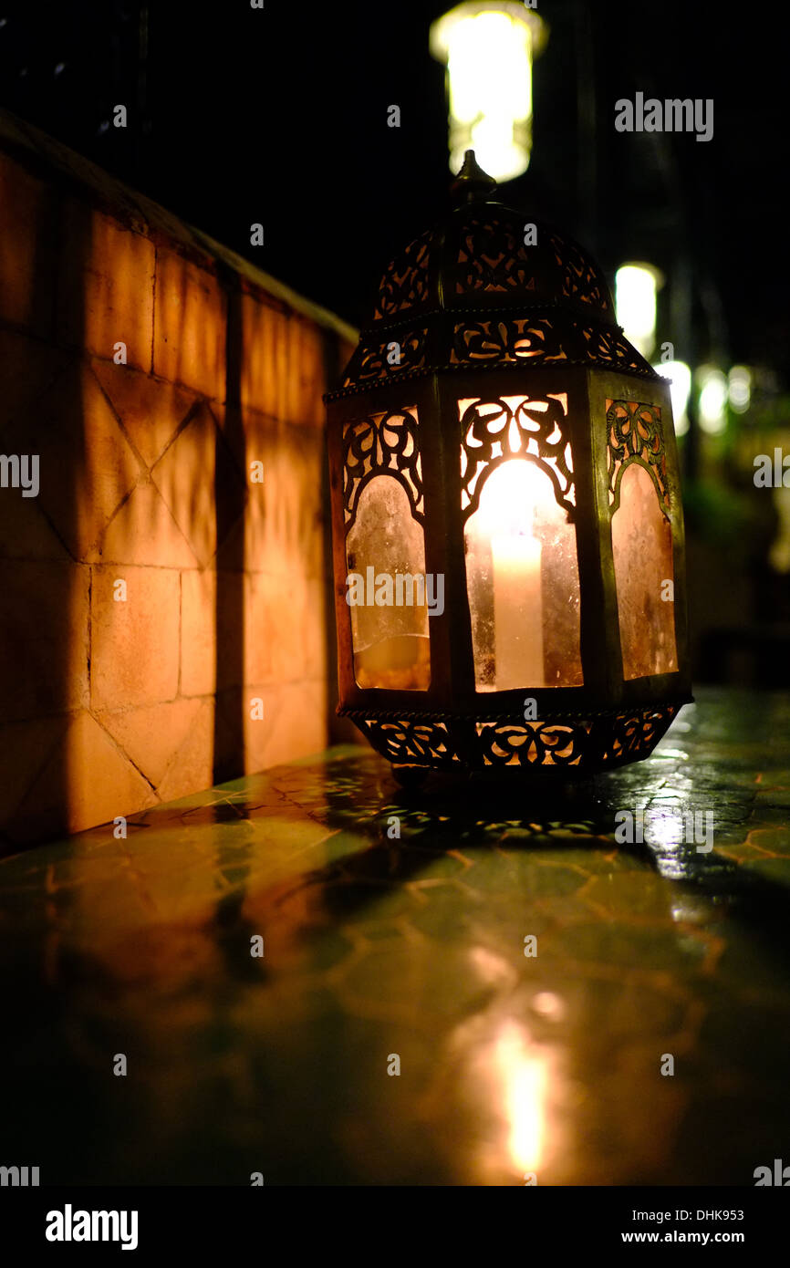Marocchino Lampada candela su una tavola contro tradizionali piastrelle marocchine in serata Foto Stock