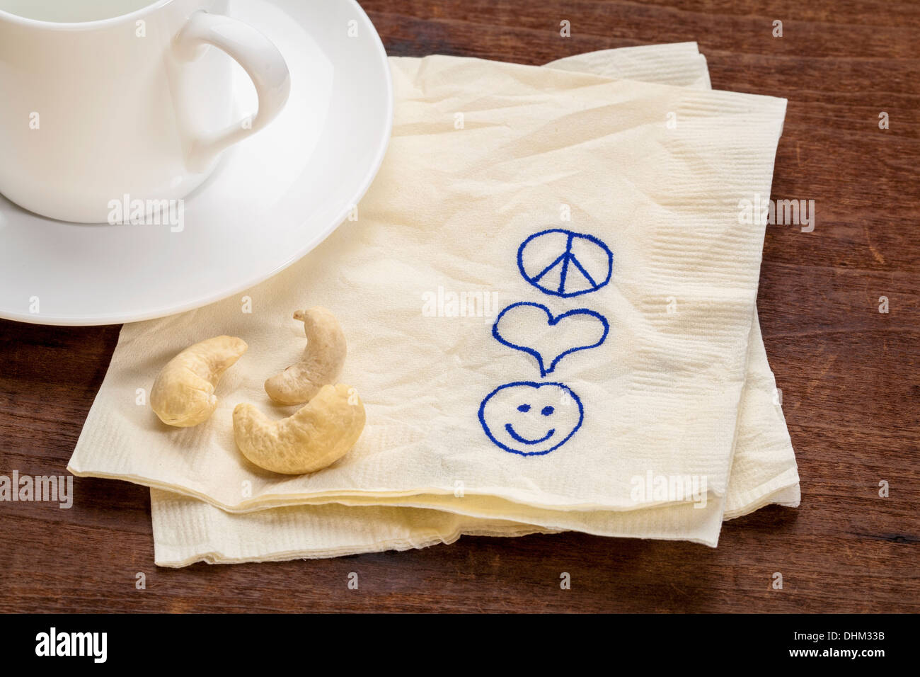 Pace amore e felicità simboli disegnò su un tovagliolo con una tazza di caffè Foto Stock