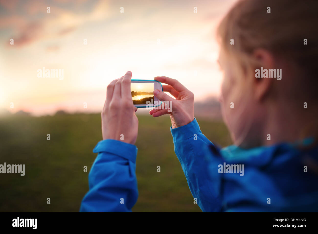 Donna di scattare le foto con il suo smartphone al tramonto Foto Stock