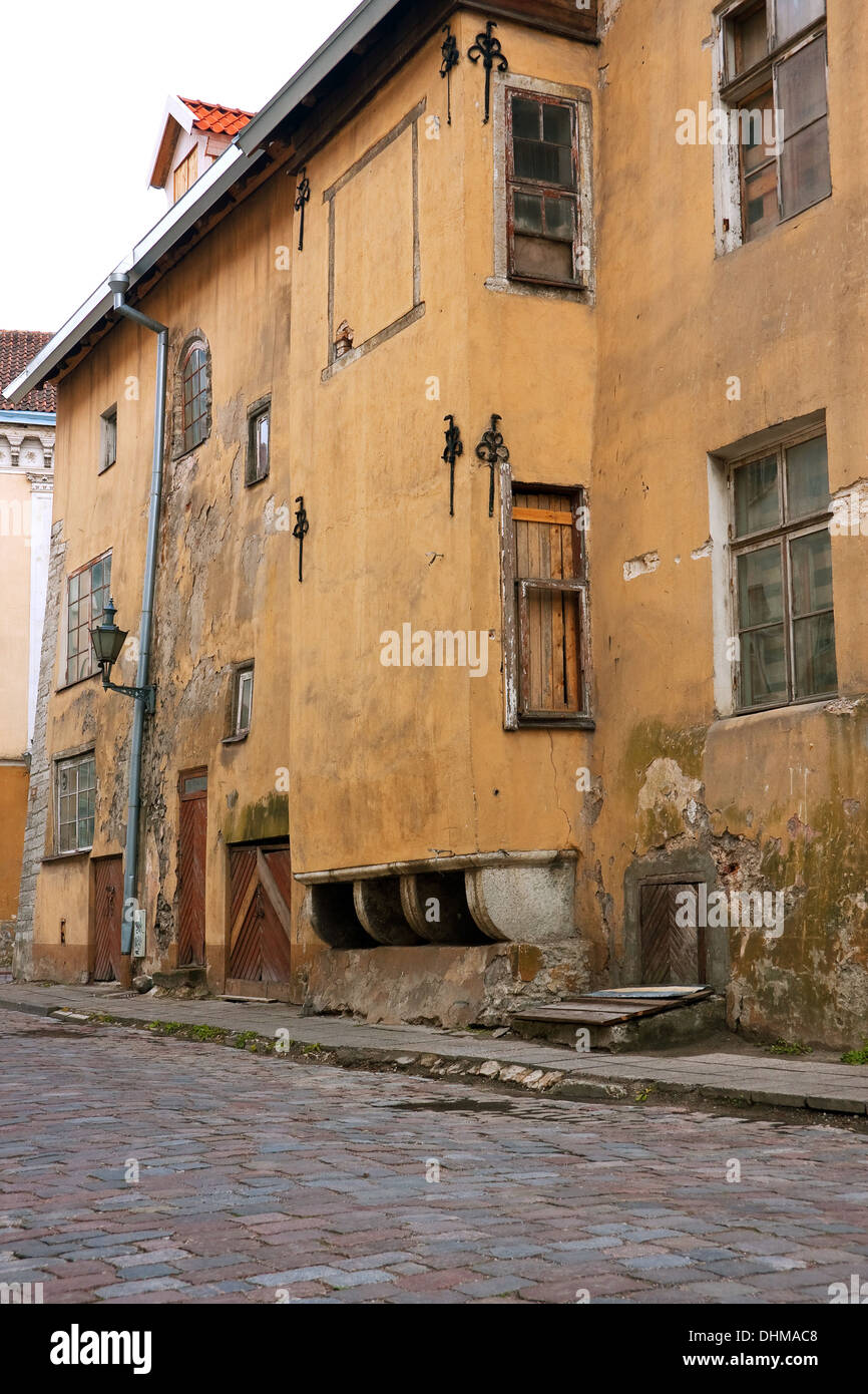 Vecchio giallo rotto abbandonato edificio a Tallinn in Estonia. Ciottoli Stone Street di fronte alla casa. Foto Stock