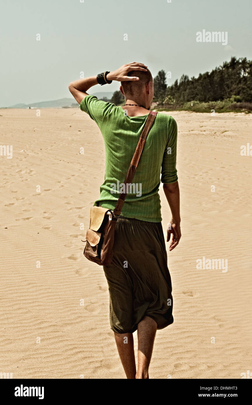 Giovane uomo che cammina su una spiaggia di sabbia Foto Stock
