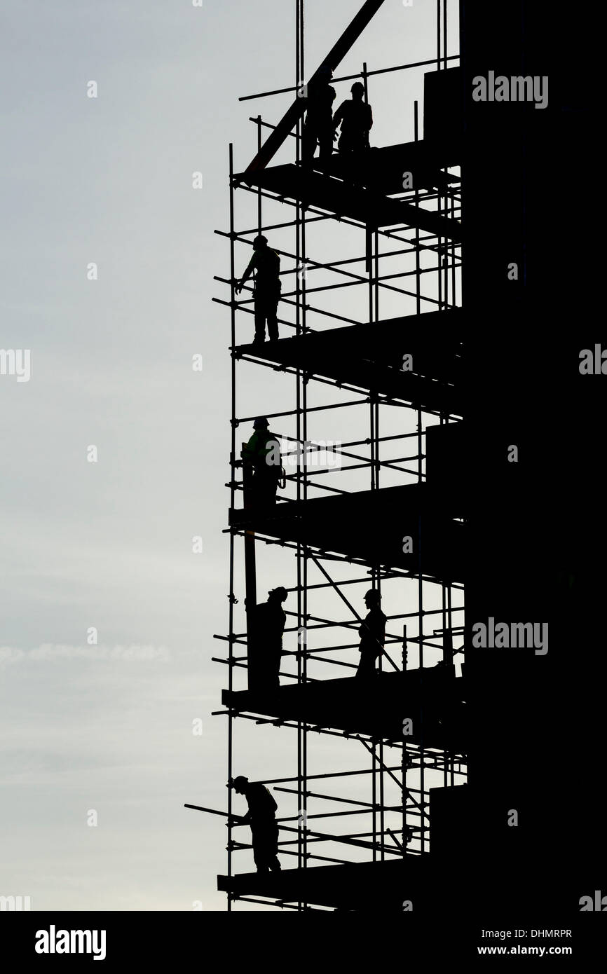 . Scaffolders lavorando sul blocco di appartamenti stagliano contro luminoso cielo autunnale Foto Stock