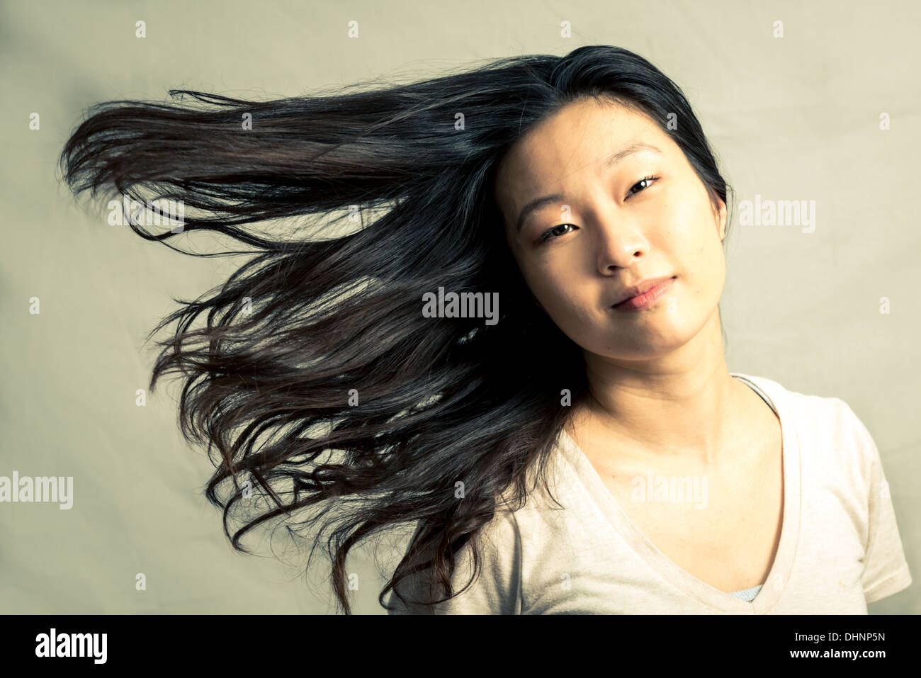 Giovane donna sfogliare i suoi capelli e posa, con tono di moda e lo sfondo Foto Stock