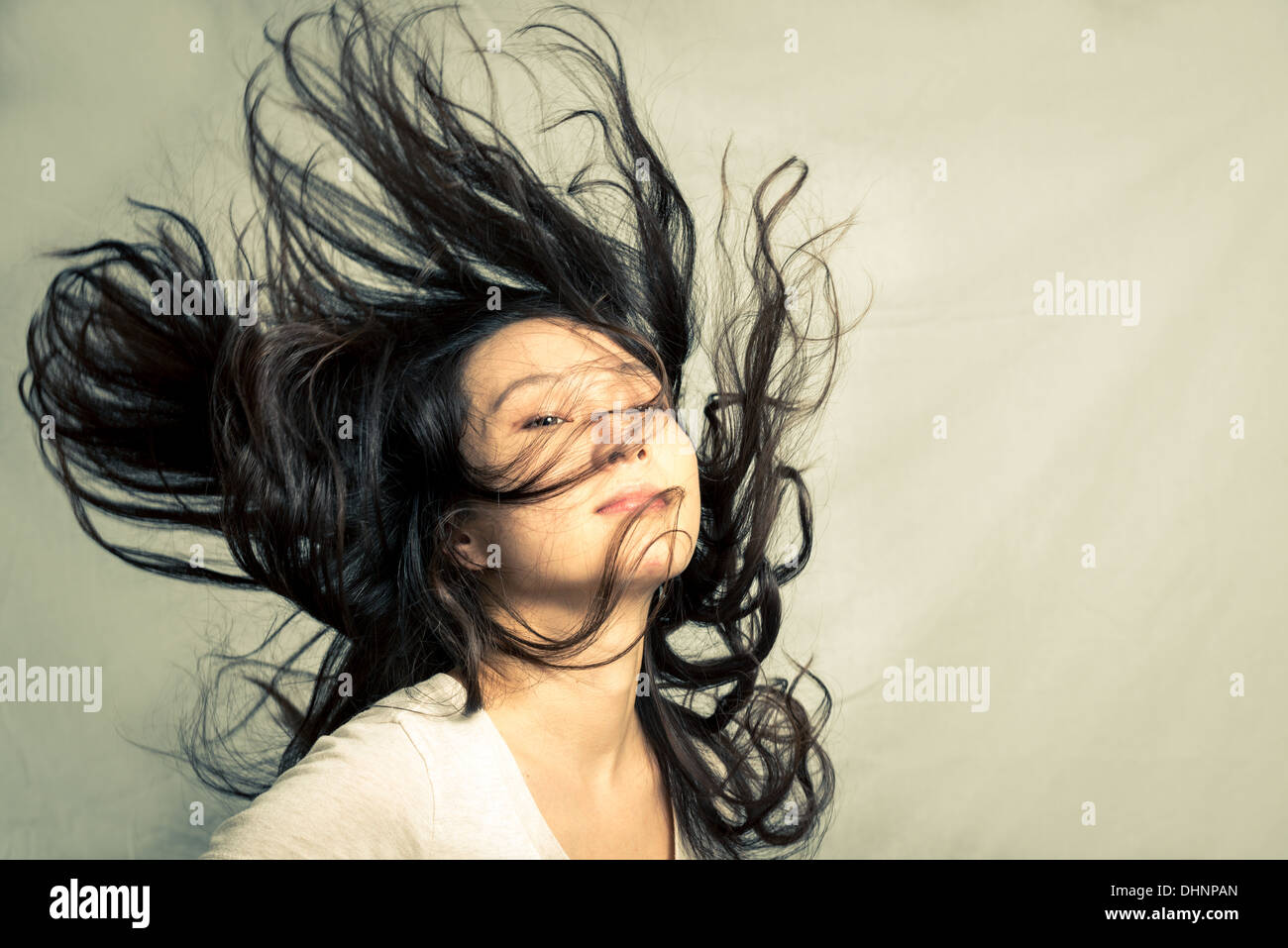 Giovane donna sfogliare i suoi capelli e posa, con tono di moda e lo sfondo Foto Stock
