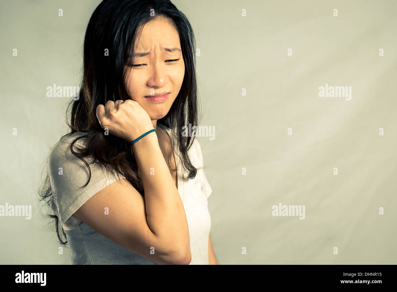 Giovane donna che piange mentre si tira i capelli, con tono di moda e lo sfondo Foto Stock