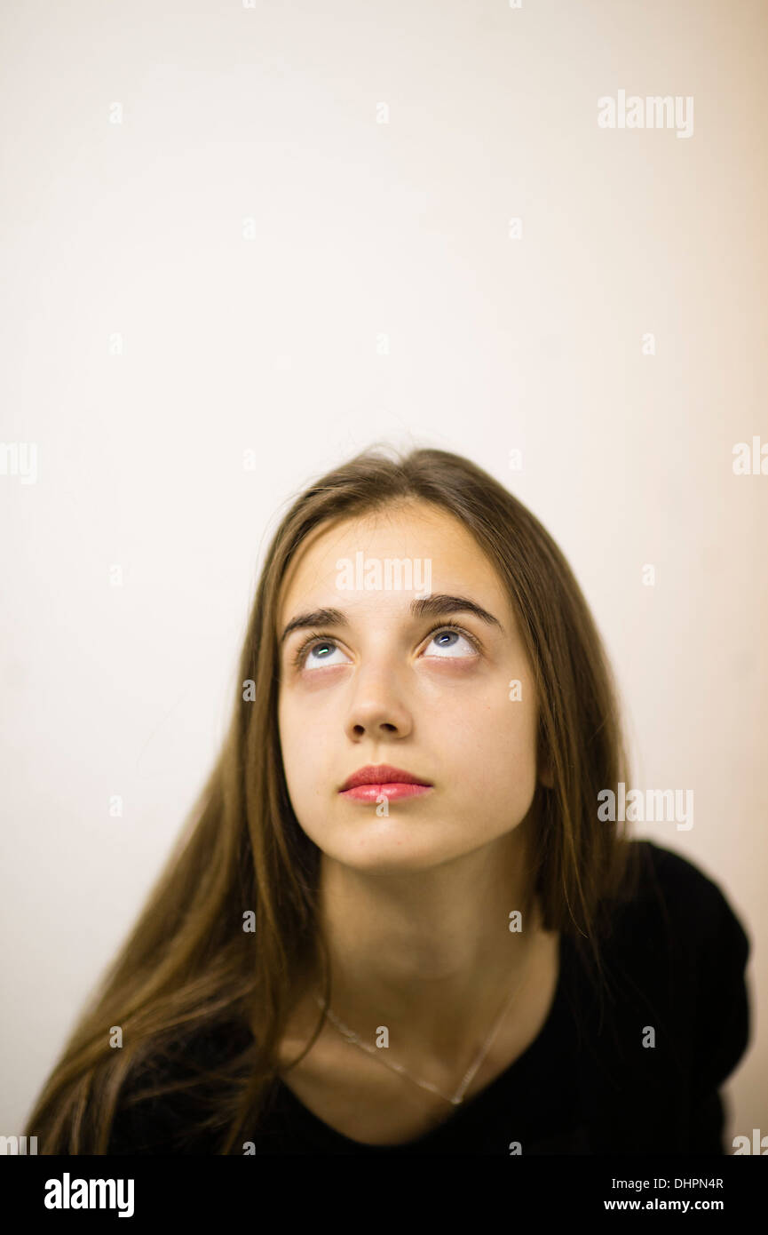 Un giovane lunghi capelli marroni caucausian donna ragazza adolescente da solo guardando verso l'alto REGNO UNITO Foto Stock