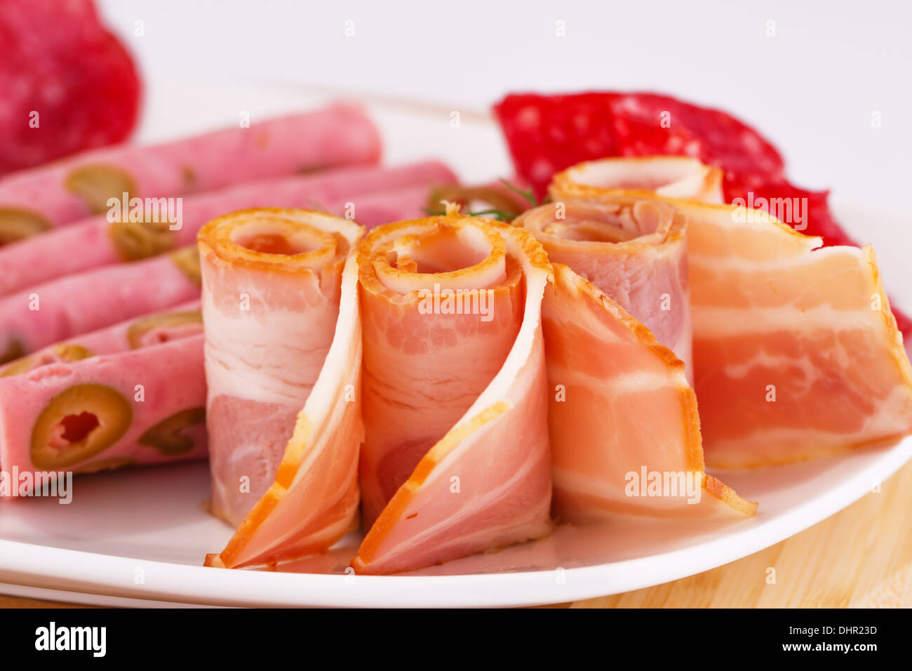 Salame, mortadella, pancetta affumicata su piastra su tavola di legno. Foto Stock