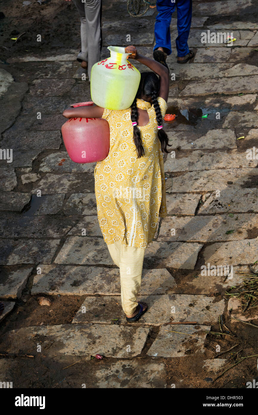 Indian ragazza adolescente portando vasi d'acqua lontano da un pozzo in una zona rurale villaggio indiano street. Andhra Pradesh, India Foto Stock