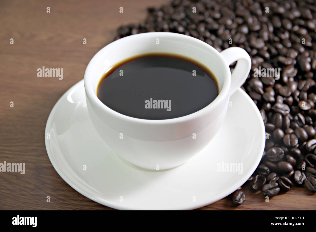 La messa a fuoco delle immagini tazza di caffè e i chicchi di caffè sul tavolo il legno vecchio. Foto Stock