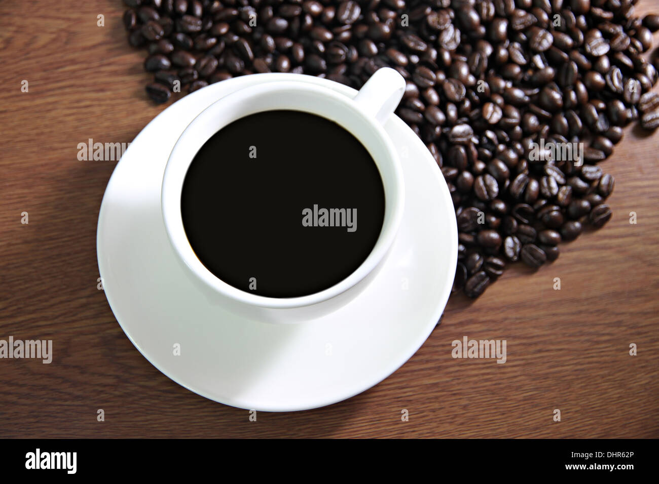 La messa a fuoco delle immagini tazza di caffè e i chicchi di caffè sul tavolo il legno vecchio. Foto Stock