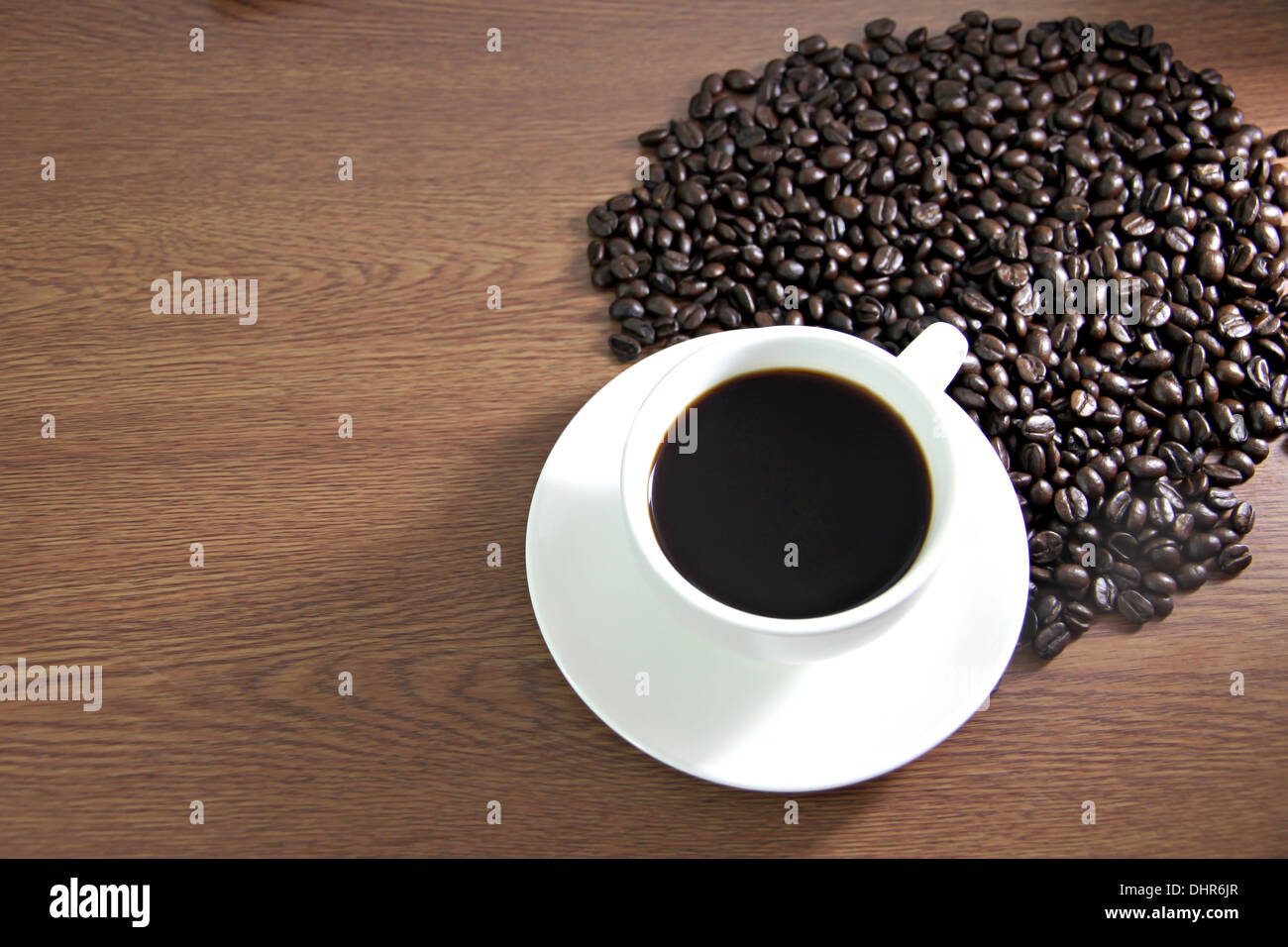 La messa a fuoco delle immagini tazza di caffè e i chicchi di caffè sul tavolo il legno vecchio. Foto Stock