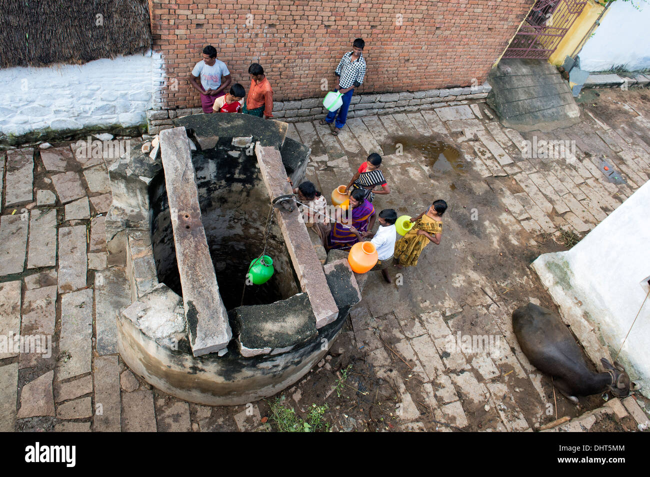 Le donne indiane, uomini e bambini il prelievo di acqua da un pozzo in una zona rurale villaggio indiano street. Andhra Pradesh, India Foto Stock