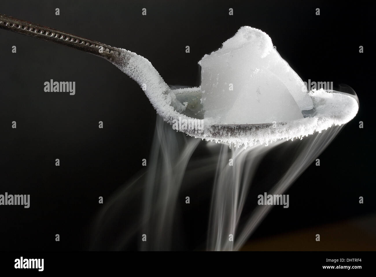 Pezzo di ghiaccio secco (biossido di carbonio congelato) sul cucchiaio di metallo. Mostra anche la presenza di ghiaccio di acqua la formazione di cristalli sul cucchiaio Foto Stock