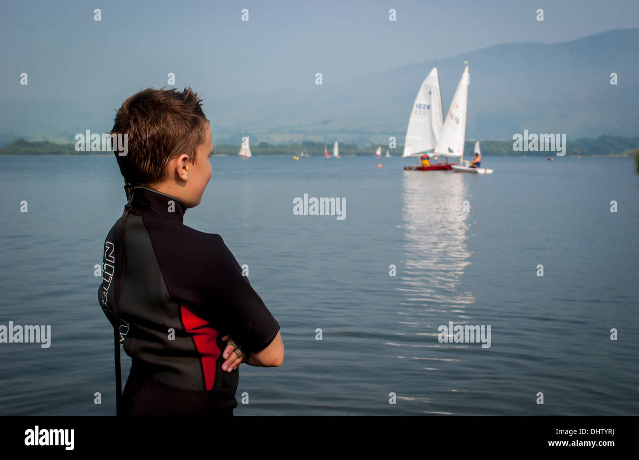 Il giovane maschio caucasico che guarda un laser e un dinghy solo si scontrano a vicenda a Bassenthwaite Lake, Cumbria, UK. Foto Stock