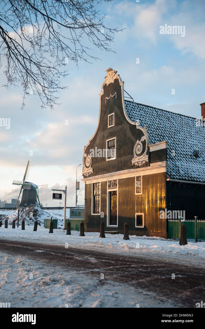 Paesi Bassi, Zaanse Schans, Zaandam, aria aperta di attrazione turistica. Mulini a vento e case. Inverno, Miller con zoccoli in bicicletta Foto Stock