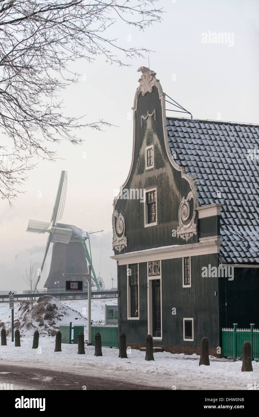 Paesi Bassi, Zaanse Schans, Zaandam, aria aperta di attrazione turistica. Mulini a vento e case. Inverno, Miller con zoccoli in bicicletta Foto Stock