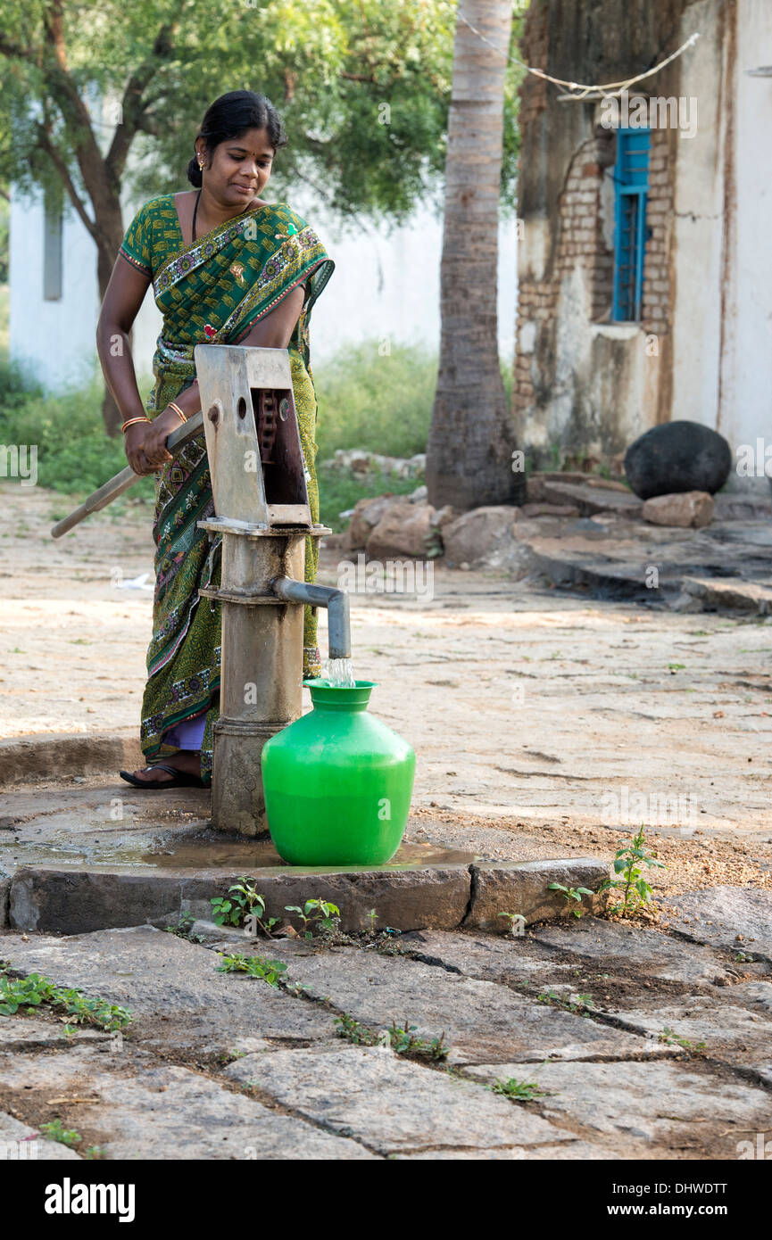 Donna indiana di riempimento acqua in plastica vaso da un villaggio rurale la pompa a mano. Andhra Pradesh, India Foto Stock