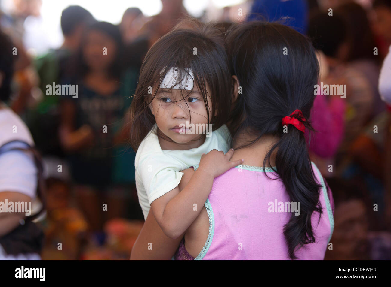 Lapu Lapu, Cebu, Filippine. Il 15 novembre 2013. Un giovane bambino in madri bracci attende di ricevere una valutazione in corrispondenza di una stazione di medici per accogliere gli sfollati a Barangay Lo-ok,Lapu Lapu,Cebu. Credito: galleria immagini2/Alamy Live News Foto Stock