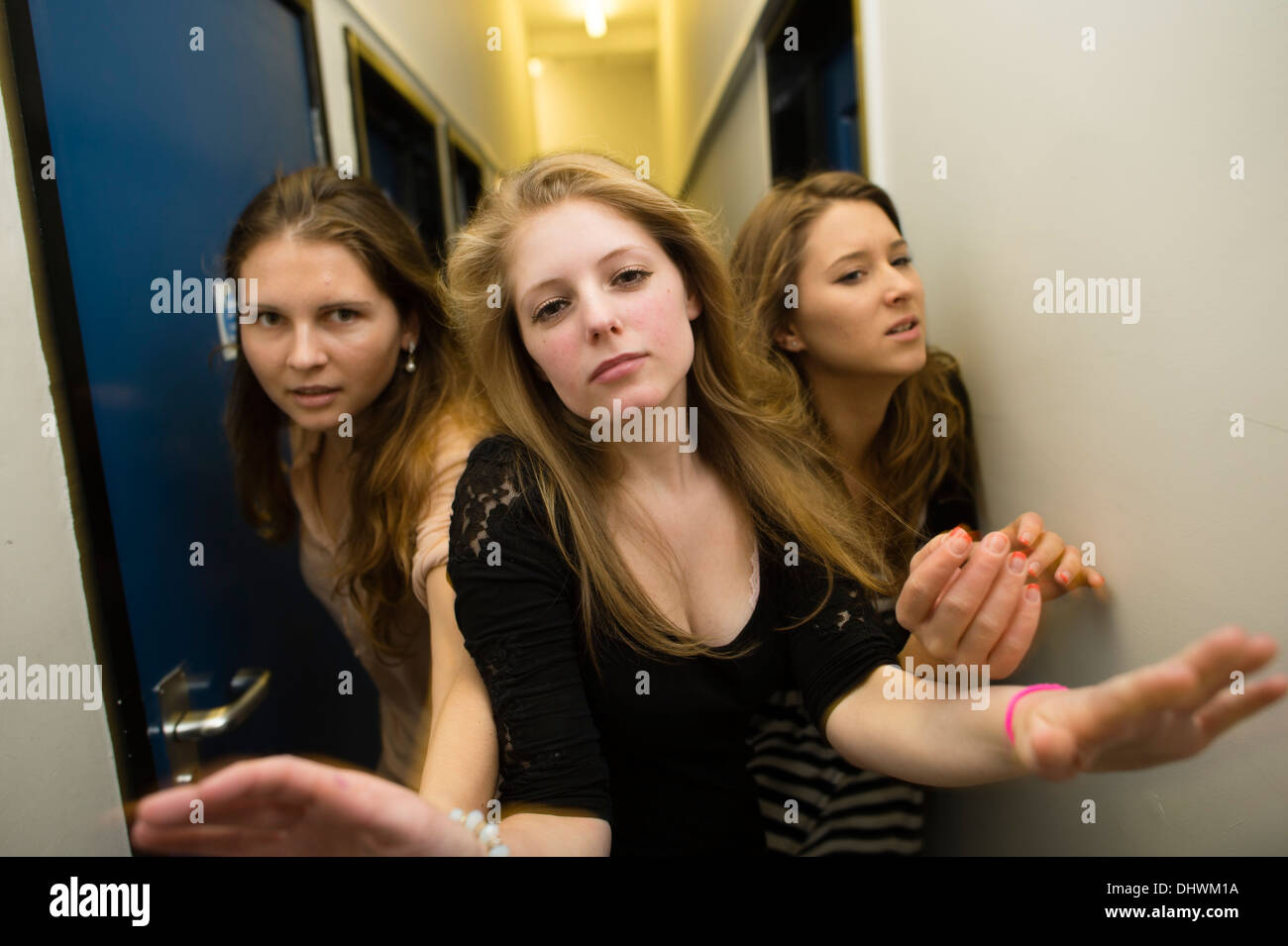 Tre giovani donne a spingere e spingendo ogni altro fuori del modo in un corridoio stretto Foto Stock