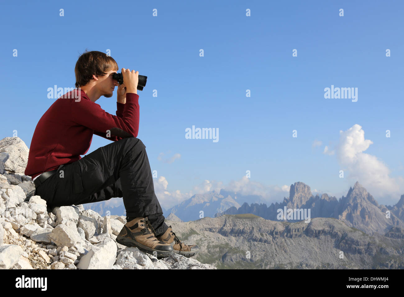 Giovane uomo cerca attraverso il binocolo in montagna Foto Stock