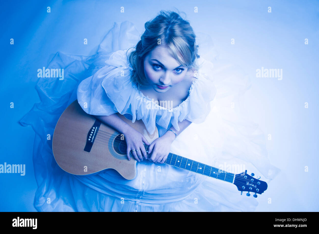 Vista aerea di una giovane donna bionda ragazza adolescente in un bianco fiaba vestito con una chitarra Foto Stock