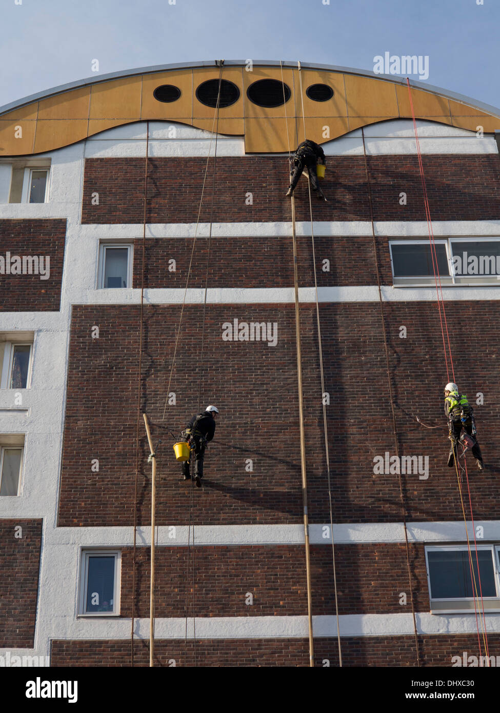 Pulizia dei lavoratori le pareti di un alloggiamento del consiglio estate in Hackney, Londra, Regno Unito Foto Stock