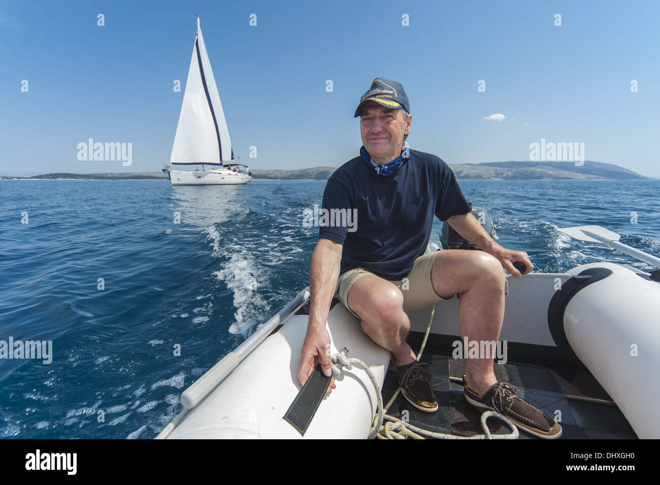Uomo alla guida di una barca accanto a uno yacht Foto Stock