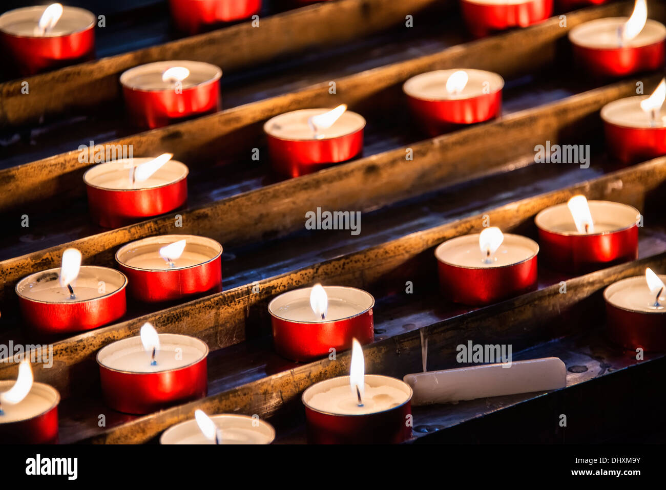 Preghiera devozionale candele in una chiesa cattolica Foto Stock