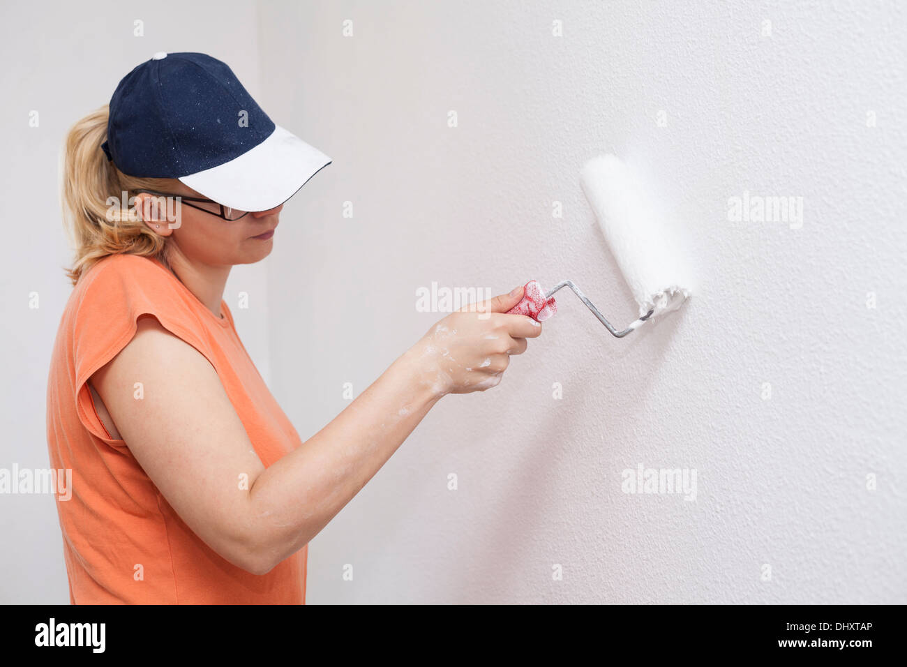 Donna pittura muro bianco con rullo di vernice. Foto Stock