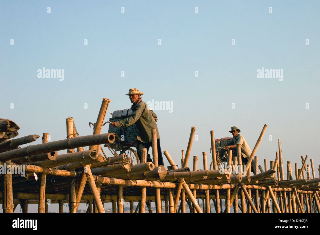 Gli uomini sono utilizzando le biciclette per il trasporto di carichi di merci su un ponte di bambù sul fiume Mekong in Kampong Cham, Cambogia. Foto Stock