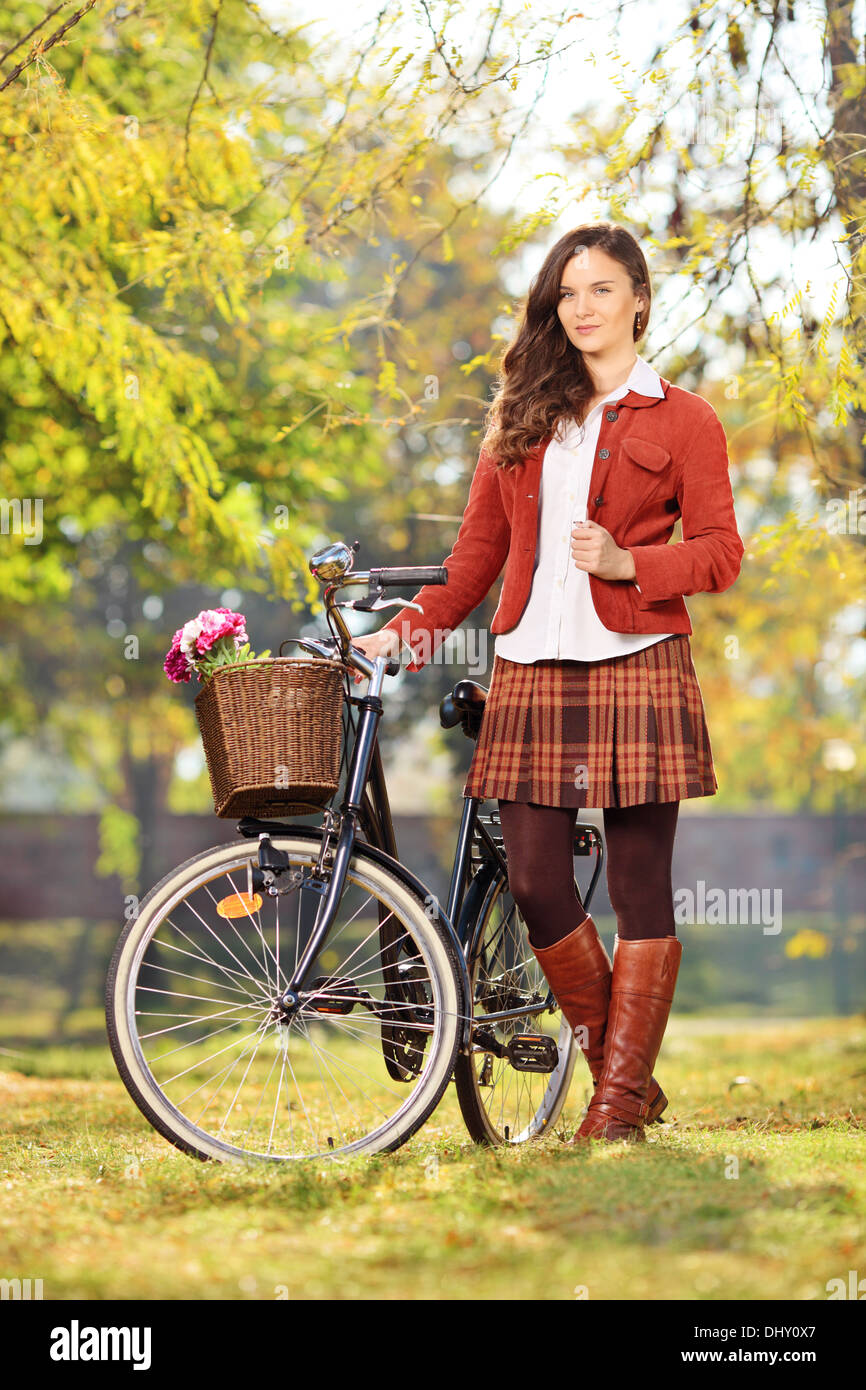 Giovane donna con la bicicletta in posa di un parco Foto Stock