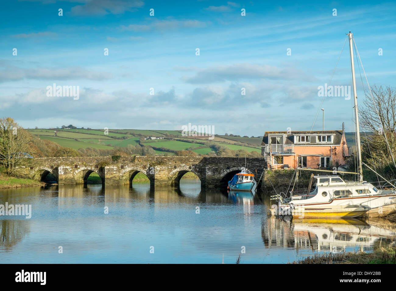 Barche ormeggiate accanto a una casa su un ponte sul fiume Avon. Aveton Gifford, Devon. Regno Unito Foto Stock