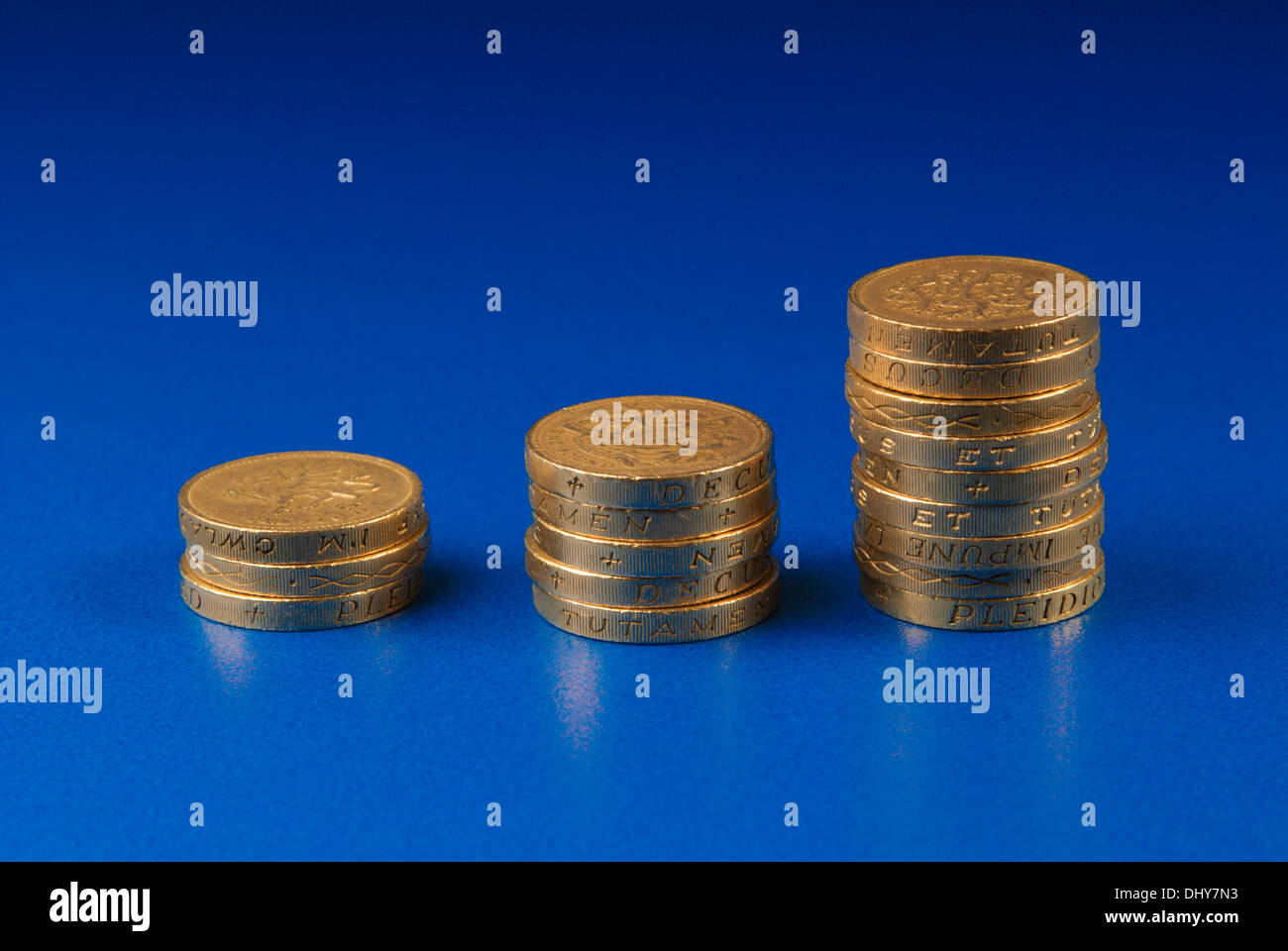 Ordine crescente di pile di monete su sfondo blu Foto Stock