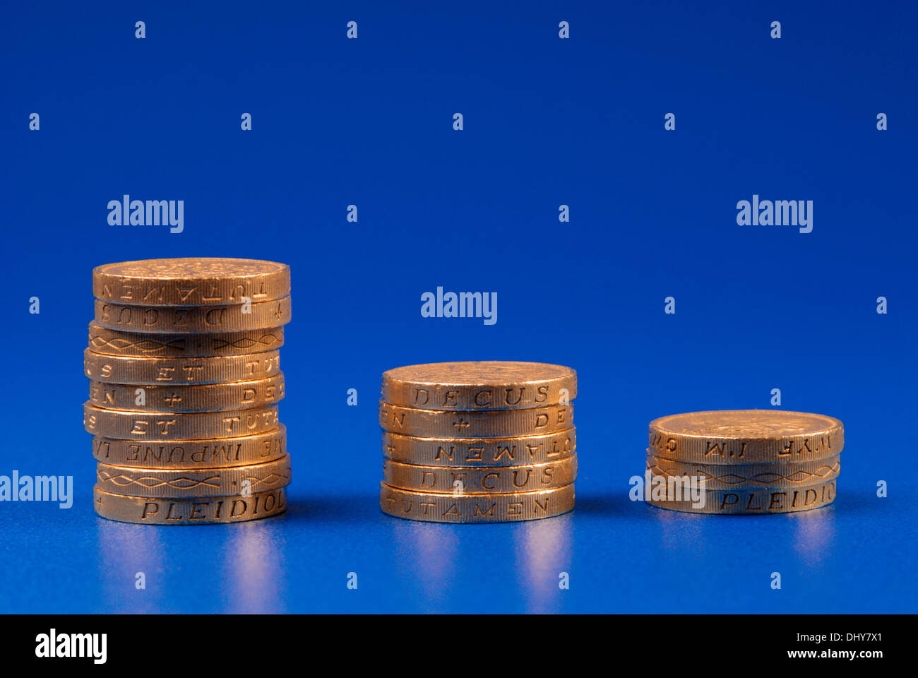 Ordine decrescente di pile di monete su sfondo blu Foto Stock