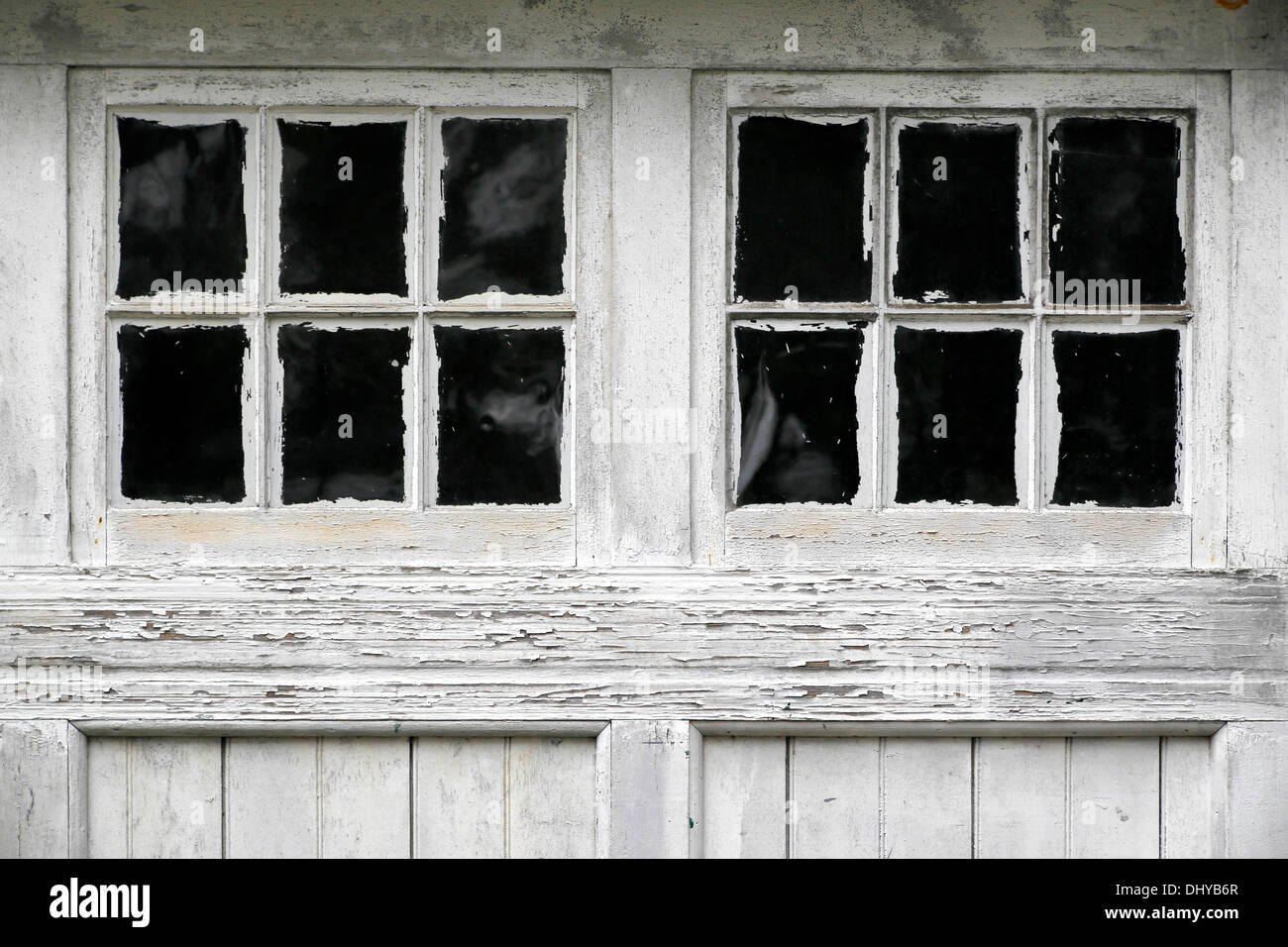 Meteo battuto vecchie porte di garage, sloppily dipinto circa i riquadri della finestra. Foto Stock