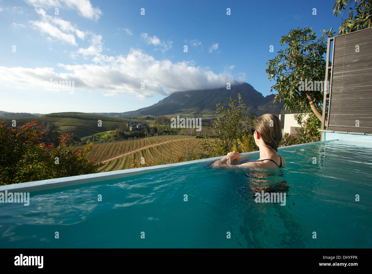 Una donna si gode della vista sopra Stellenbosch Winelands da una piscina infinity in Sud Africa. Foto Stock