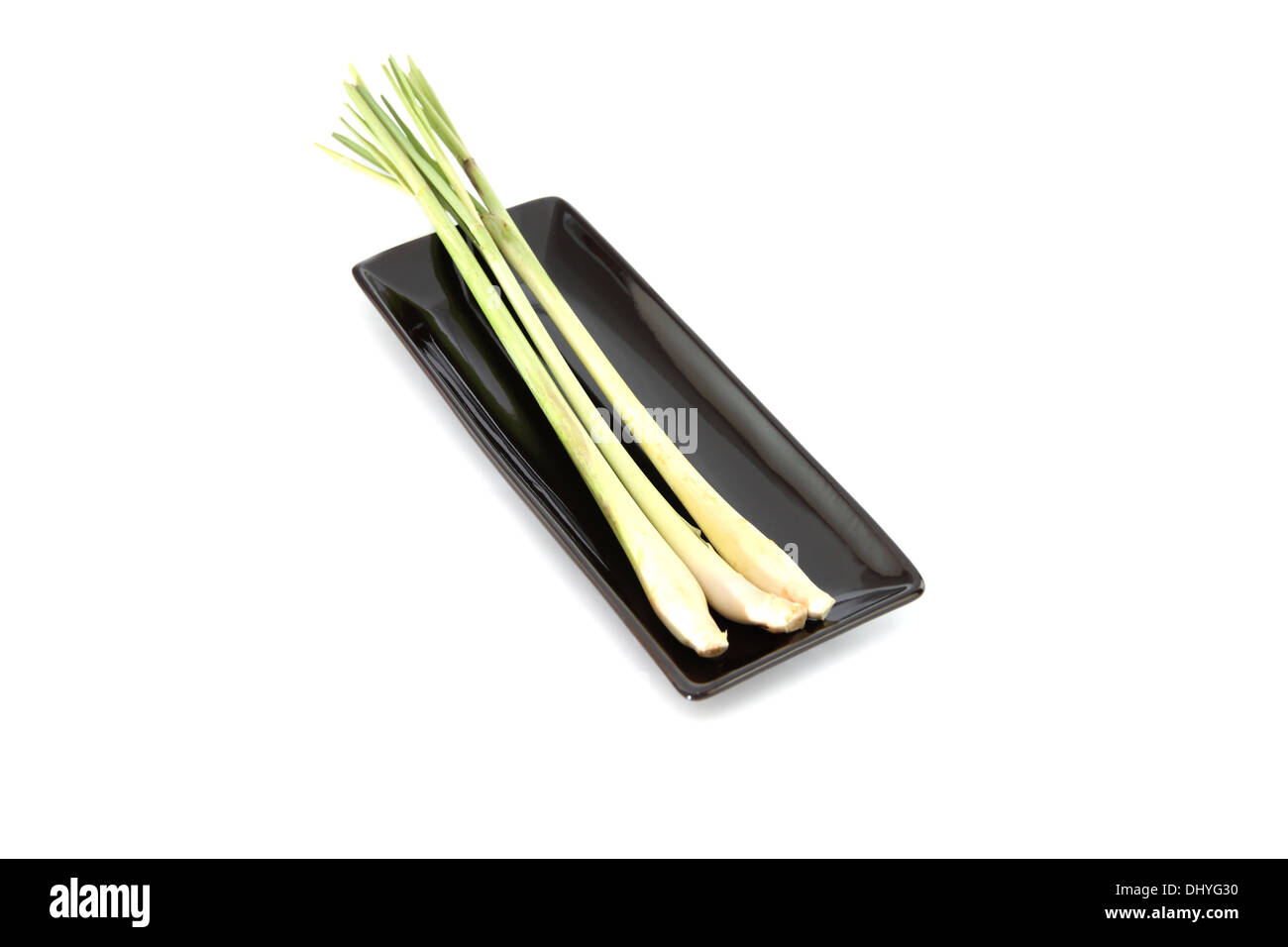 Primo piano di limone fresco in erba piatto nero su sfondo bianco. Foto Stock