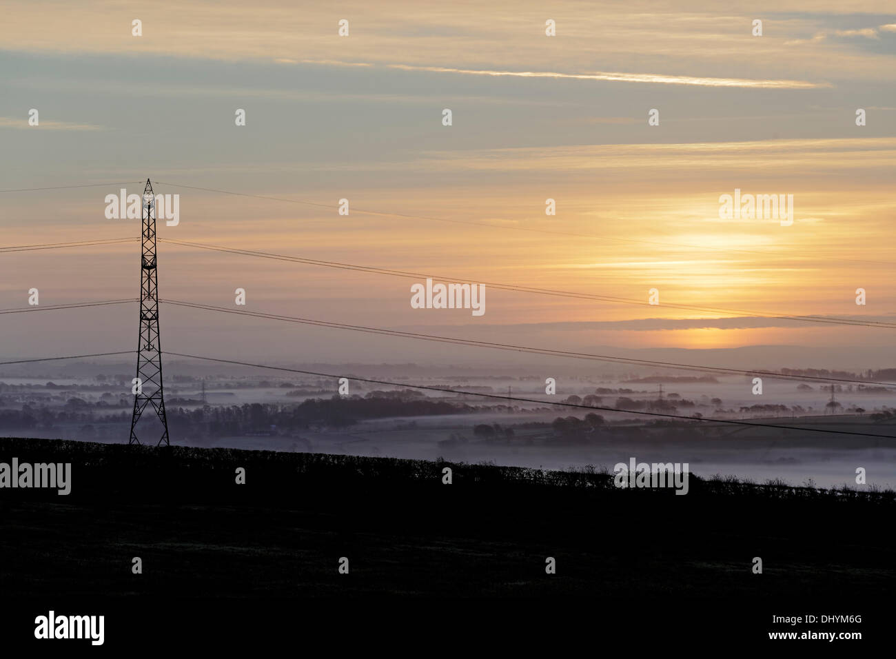 Kilbirnie, Nord Ayrshire, Scozia, Regno Unito, domenica 17 novembre 2013. Alba su un traliccio di elettricità in una valle di Gannock nebbiosa Foto Stock