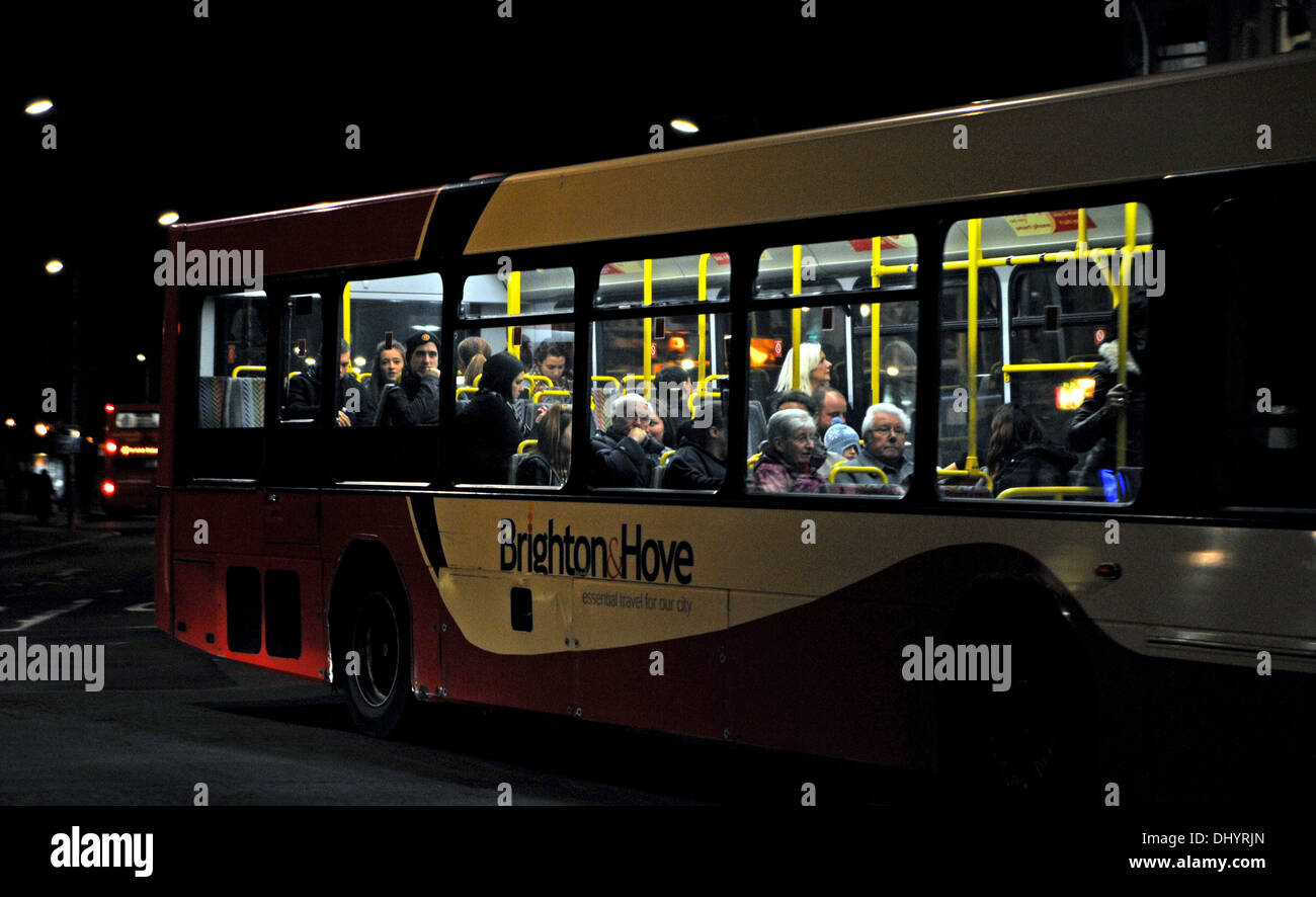 Passeggeri di un autobus stare fuori dalla loro casa di pendolarismo in Brighton di notte Foto Stock