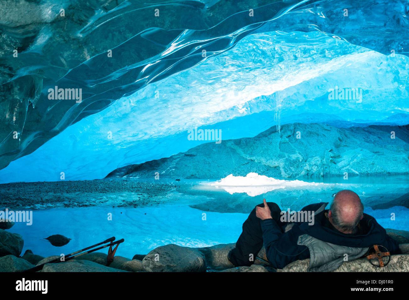 Senior uomo appoggiato all'interno di una caverna di ghiaccio, Nigardsbreen Glacier, Norvegia Foto Stock