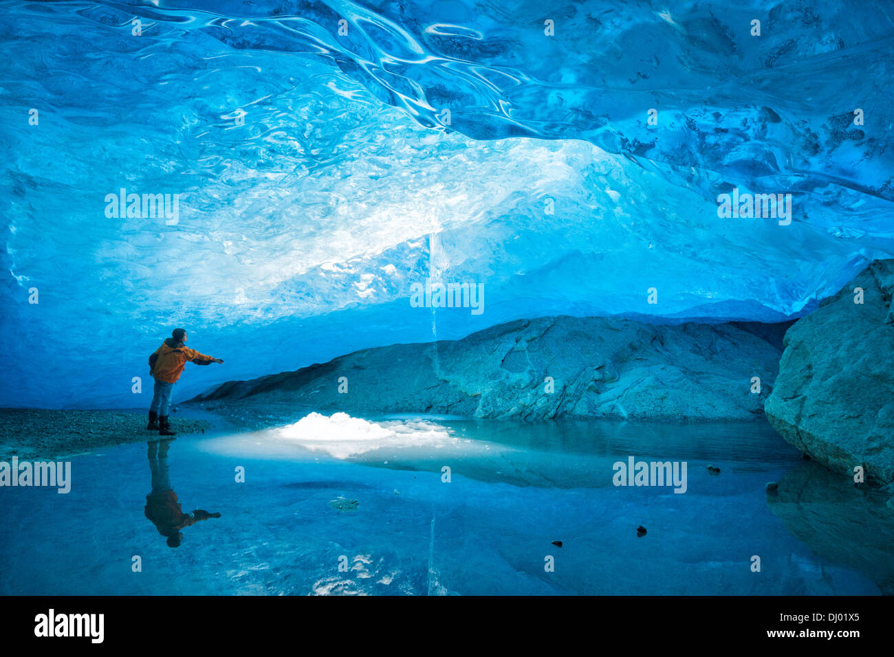 Donna in piedi all'interno di una caverna di ghiaccio al ghiacciaio Nigardsbreen e raggiungimento di ghiaccio, a Jostedalsbreen, in Europa la più grande calotta di ghiaccio, Foto Stock