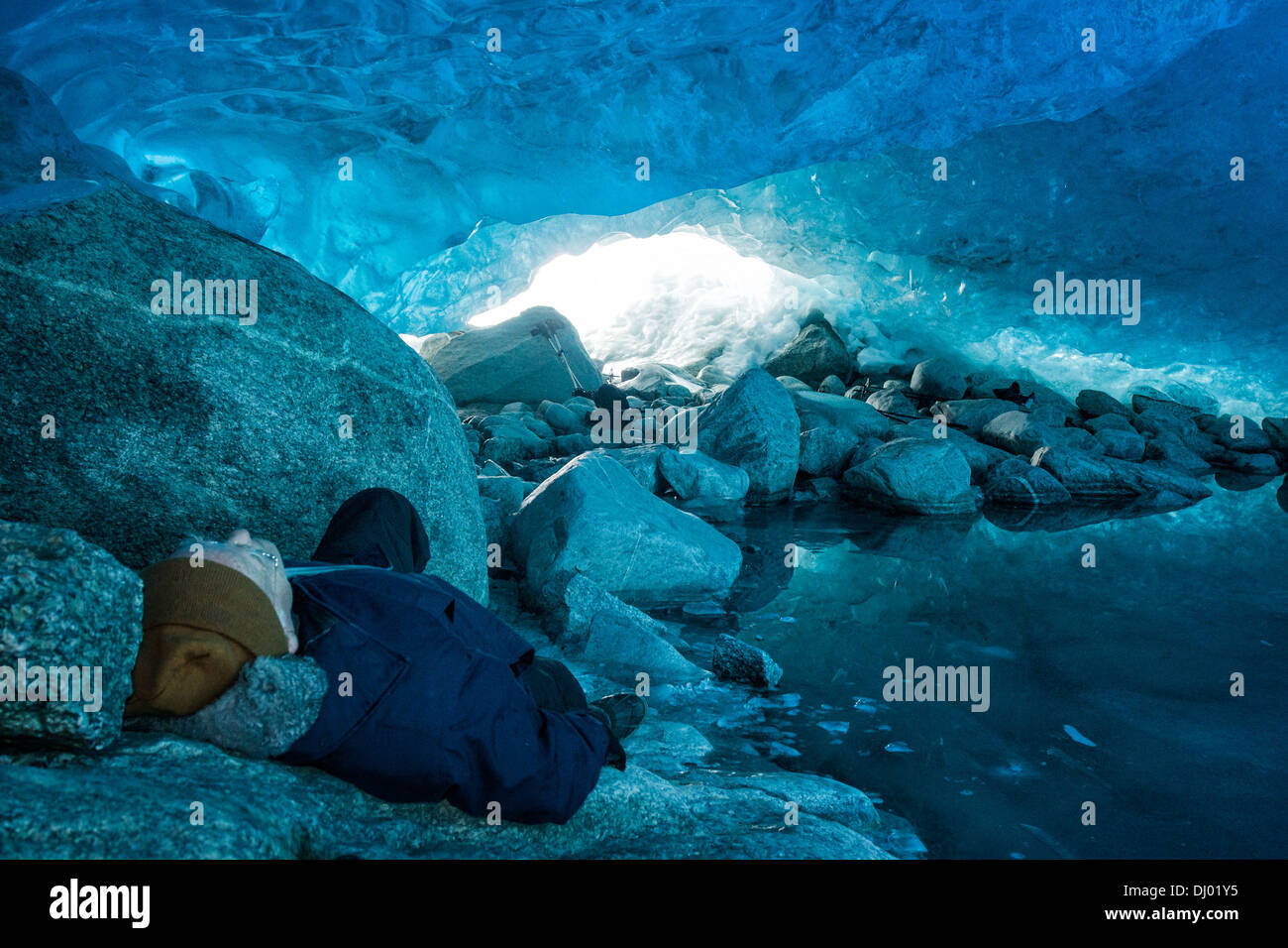 Senior uomo appoggiato all'interno di una caverna di ghiaccio al ghiacciaio Nigardsbreen, a Jostedalsbreen, Norvegia Foto Stock